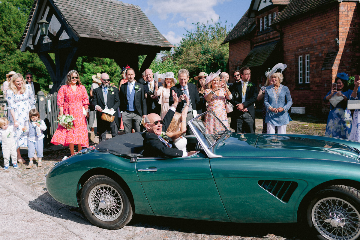 bride and groom leaving church in the vintage green wedding car