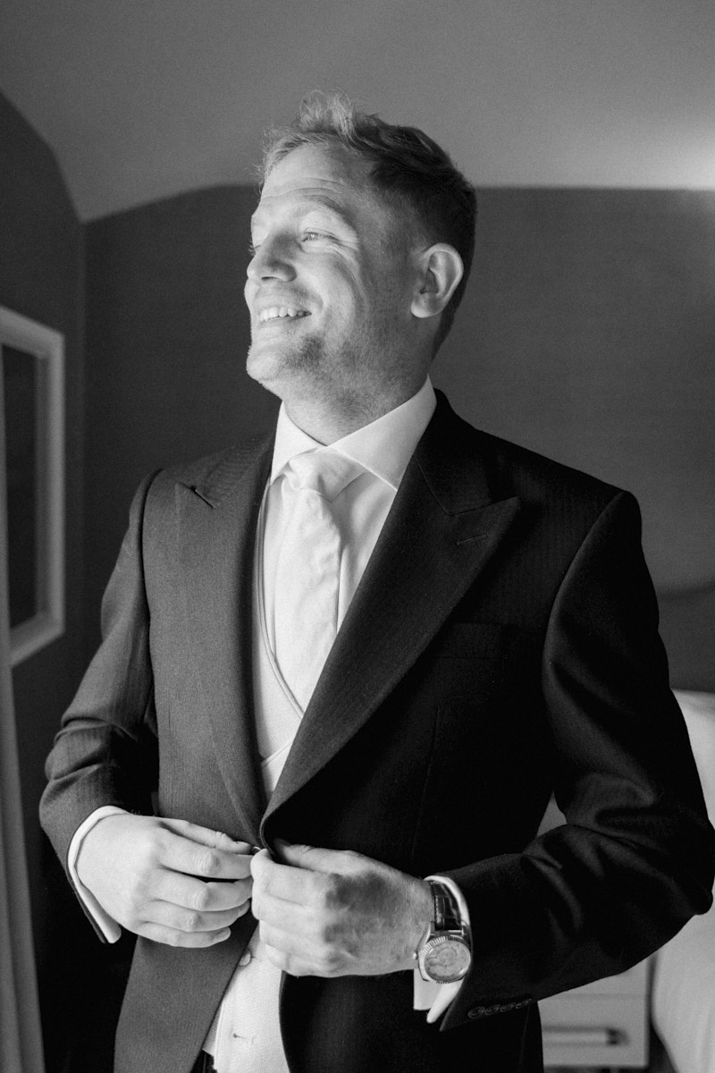 black and white photo of the groom getting ready in the falcon hotel in castle ashby