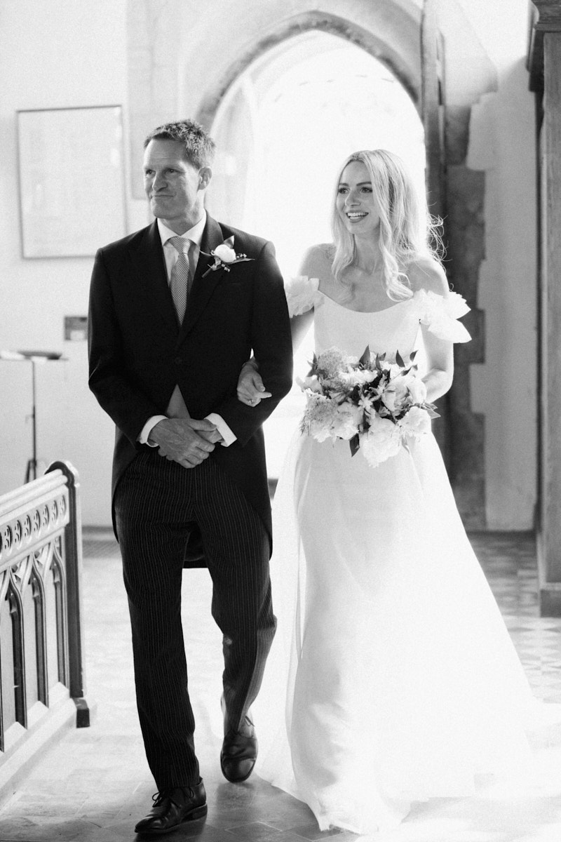 black and white photo of bride and father walking down the isle