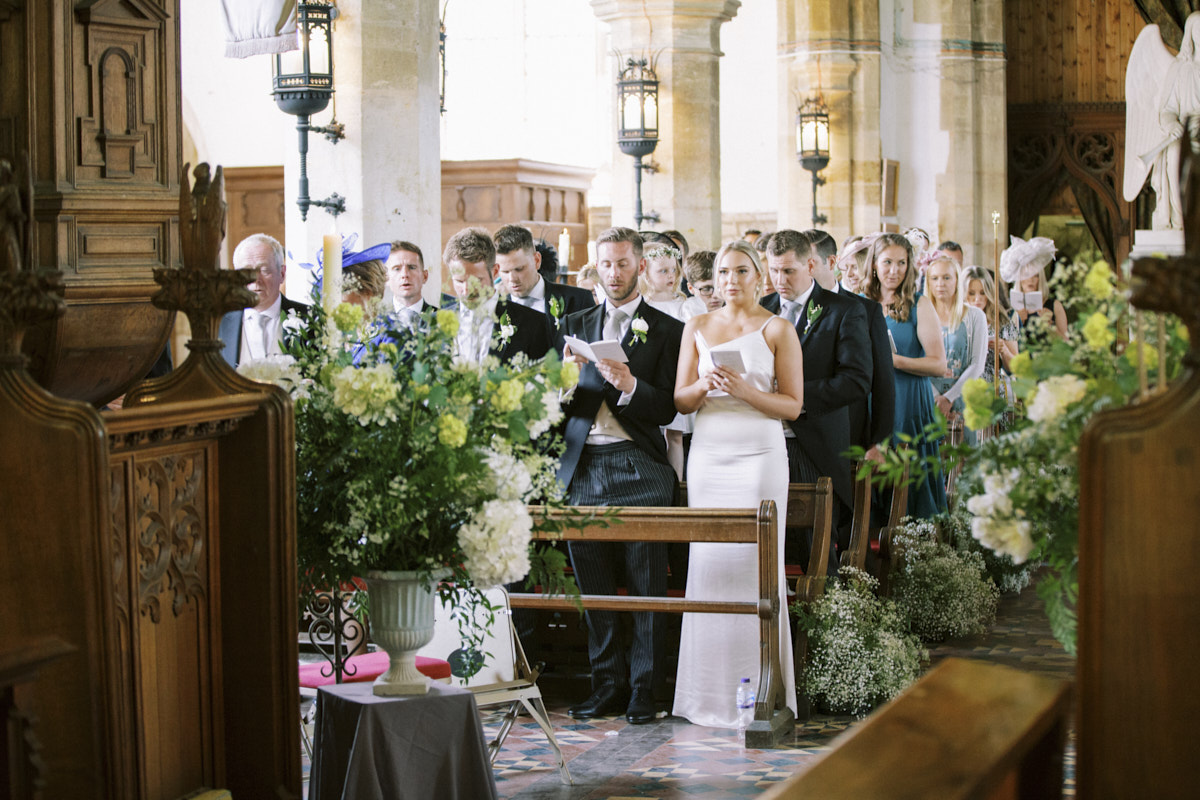 wedding guests singing songs during church wedding ceremony at castle ashby
