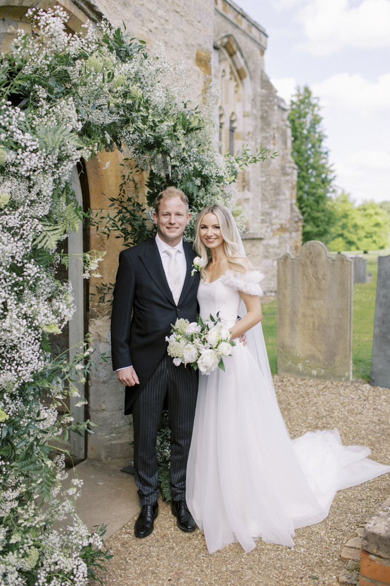 bride and groom in front of the st mary magdalene church in castle ashby