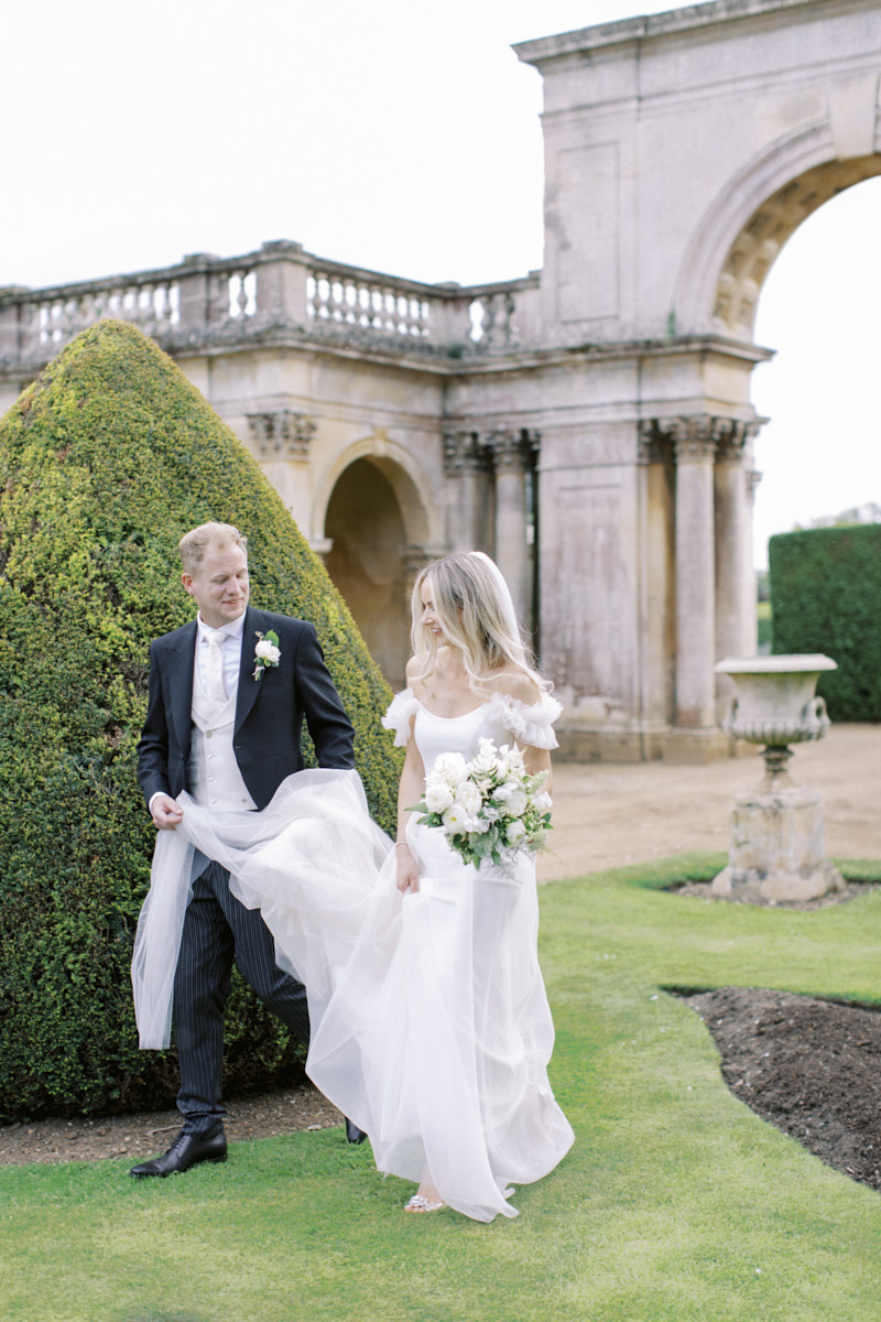 bride and groom walking through castle ashby gardens after the wedding ceremony 
