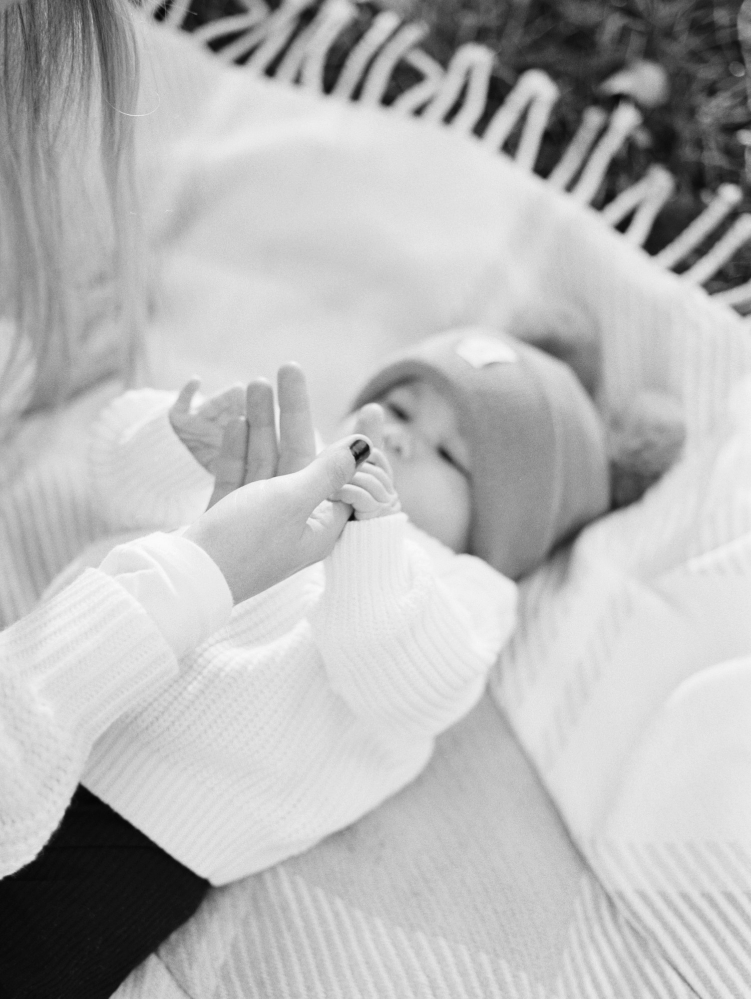black and white photo of mother holding baby girl hand