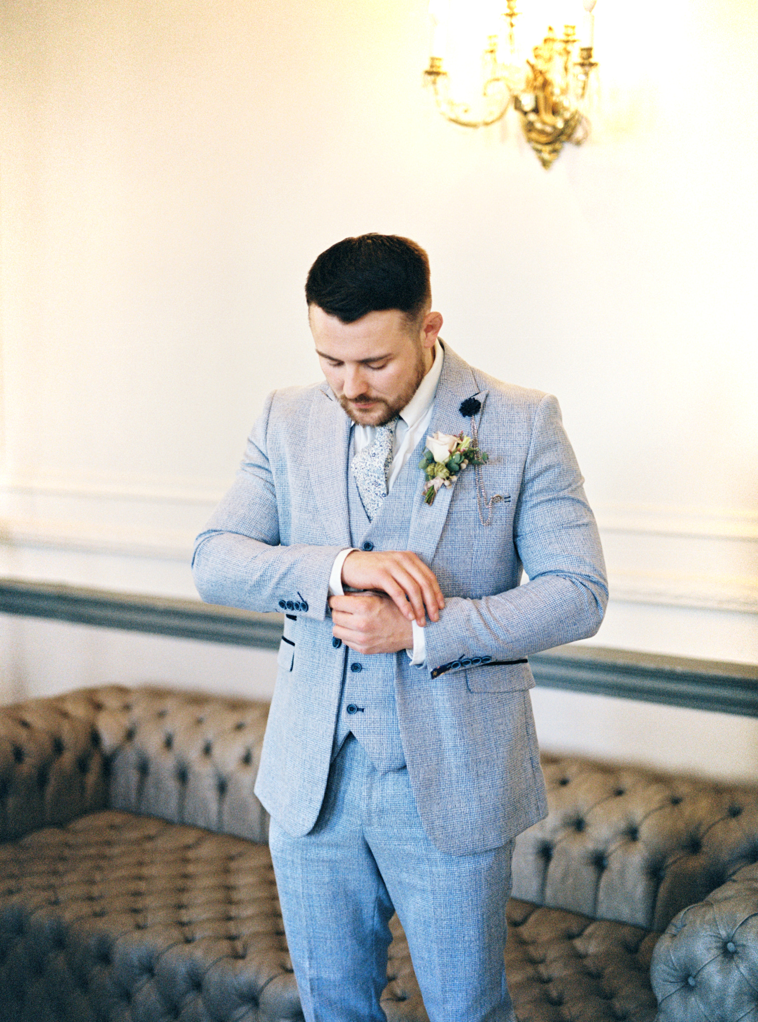 groom wearing blue suit with a tie standing and preparing for wedding ceremony