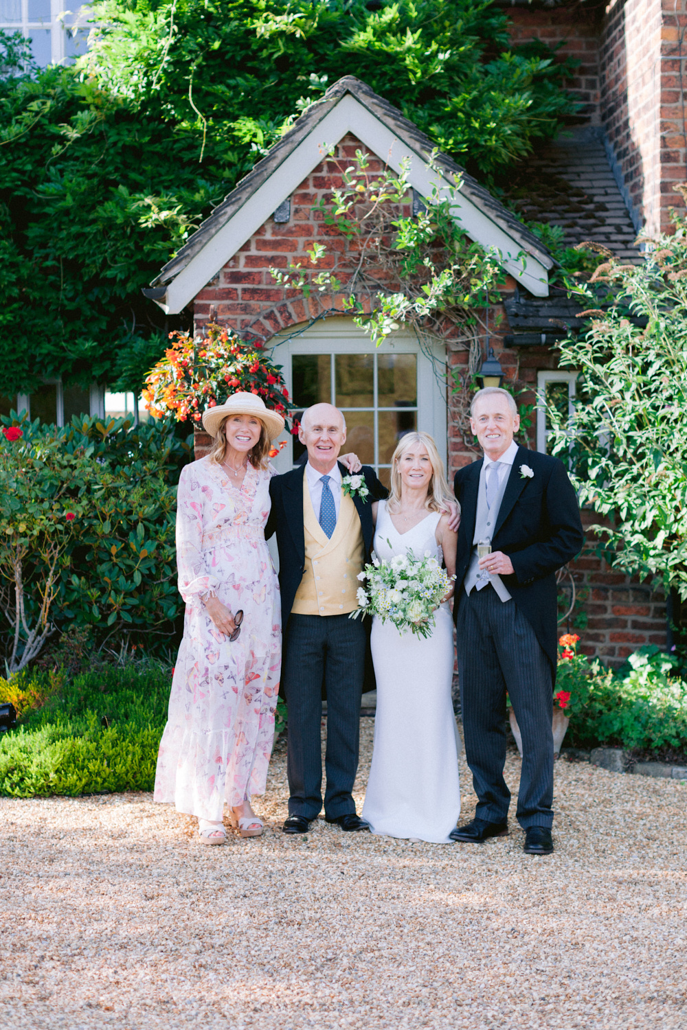 elderly bride and groom posing with friends in front of family home