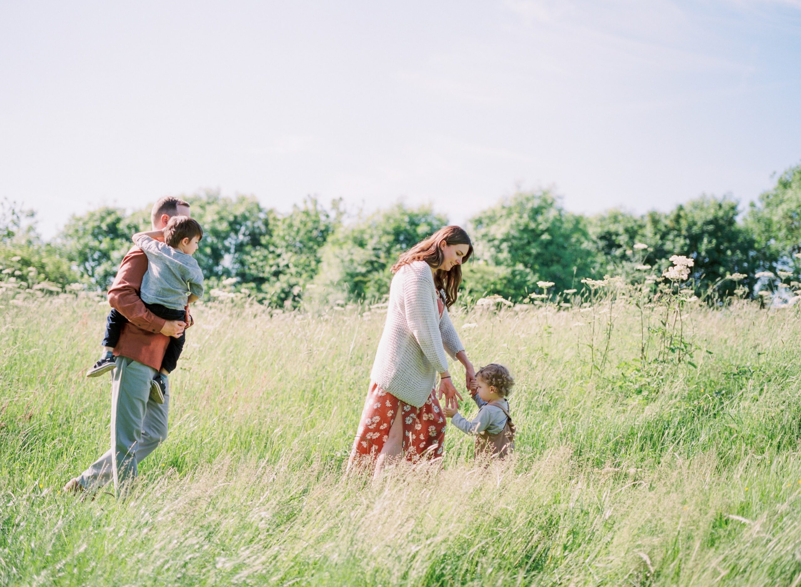 family of four walking through meadow at their family photoshoot birmingham