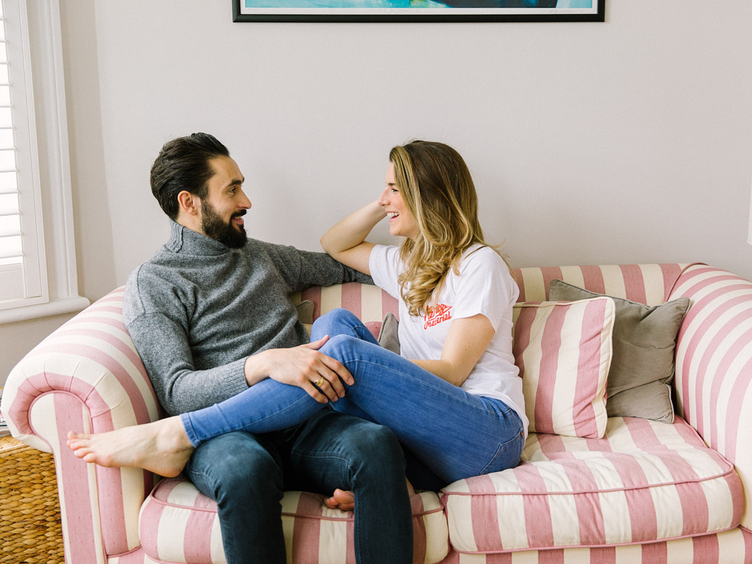 couple sitting on the pink colour stipe sofa and looking at each and smiling