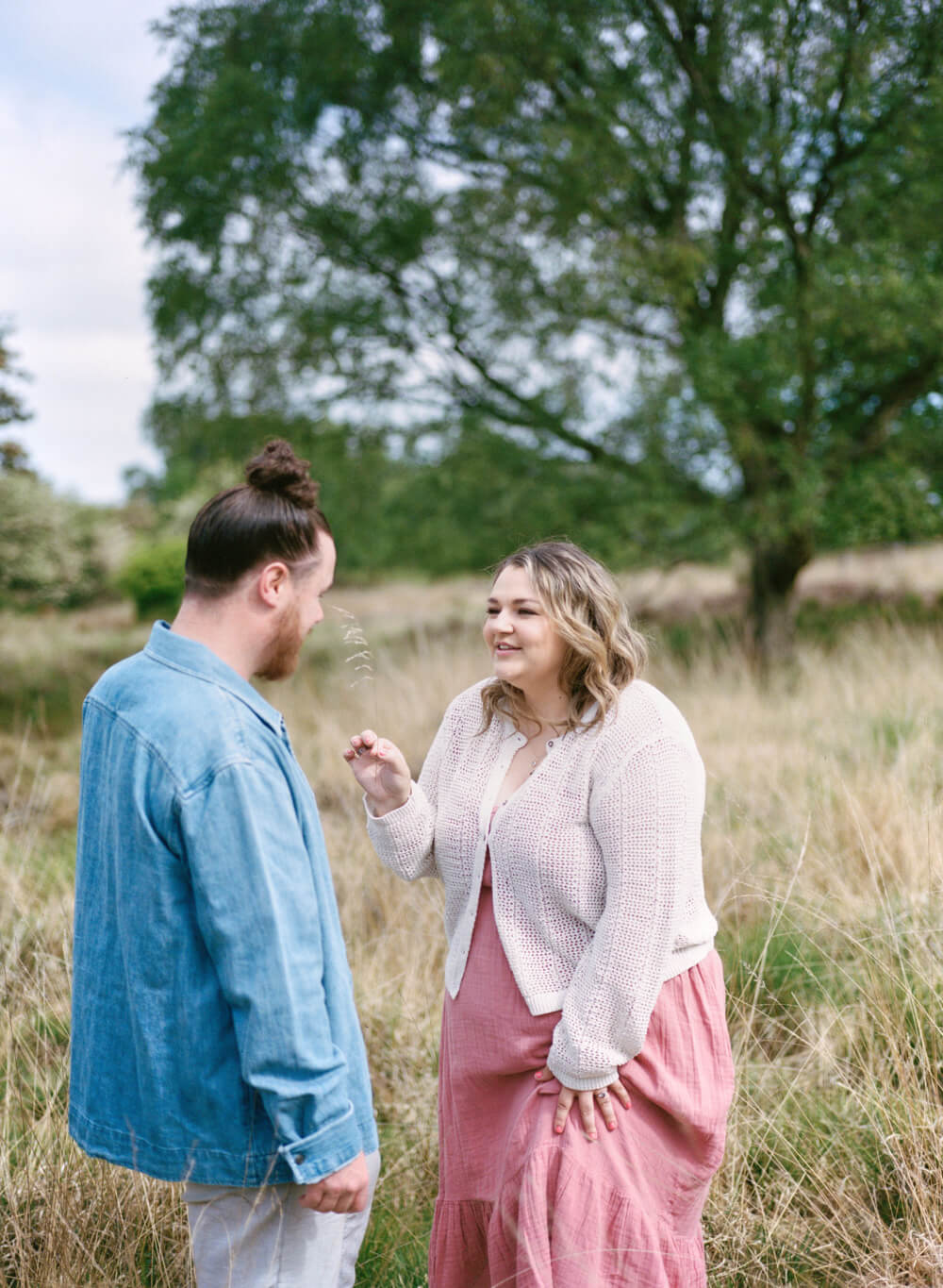 bride to be tickling fiance nose with long grass