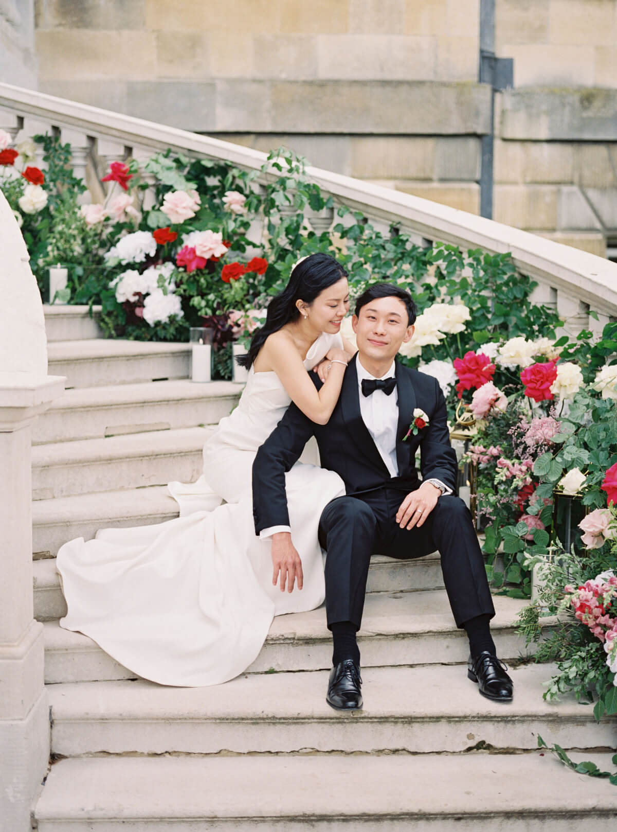 relaxed and natural bride and groom portrait sitting on the grand staircase decorated with flower arrangement on each step